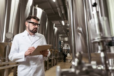 Ciddi adam bira fabrikasında notlar yapma