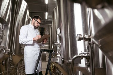 Merdiven kullanma ve bira fabrikası'nda mekanizması memnun adam