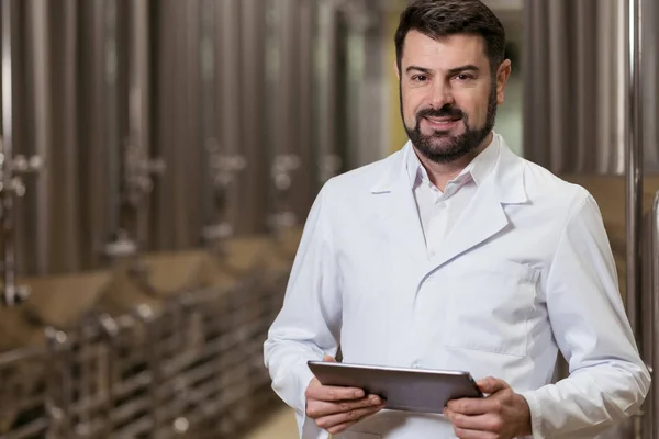 Concentrated man posing with tablet in brewery — Stock Photo, Image