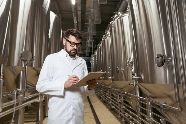 Handsome man making notes in brewery — Stock Photo, Image