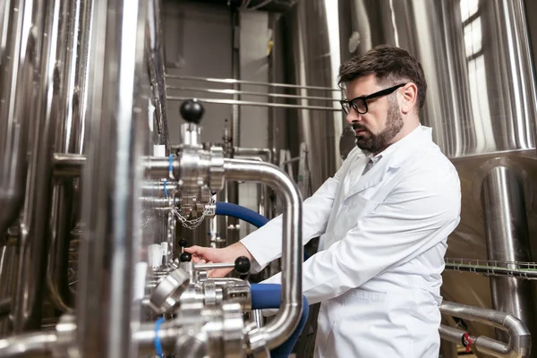 Uomo laborioso utilizzando il meccanismo di produzione della birra — Foto Stock