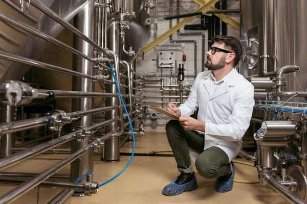 Hombre concentrado sentado en la fábrica de cerveza — Foto de Stock