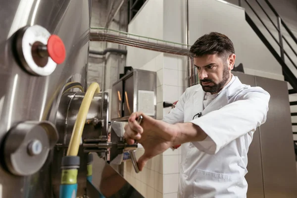 Ernsthafter Mann öffnet Zapfhahn in Bierfabrik — Stockfoto