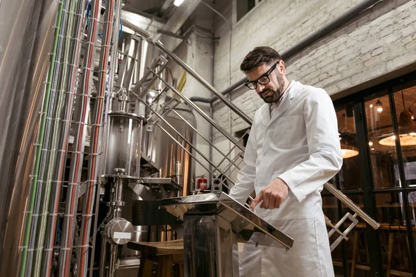 Homem sério pressionando botões na fábrica de cerveja — Fotografia de Stock