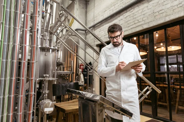 Homem sério observando resultados na fábrica de cerveja — Fotografia de Stock