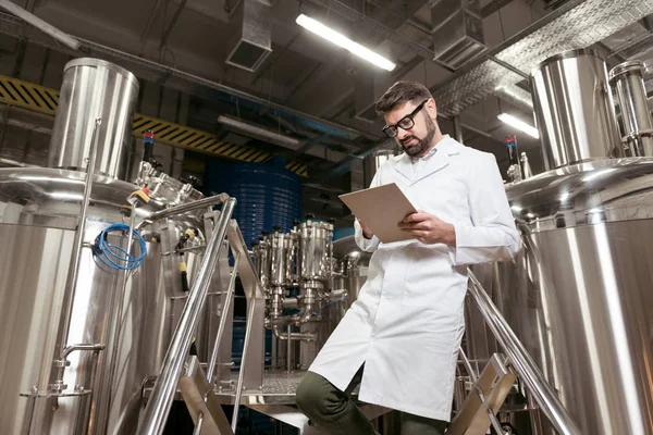 Homem satisfeito fazendo anotações na fábrica de cerveja — Fotografia de Stock