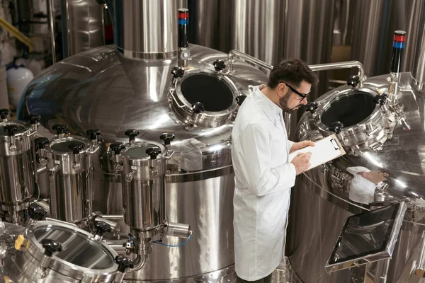 Concentrated man controlling mechanisms at beer factory — Stock Photo, Image