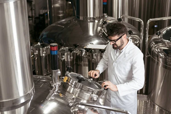 Satisfied man using brewing mechanism at factory — Stock Photo, Image