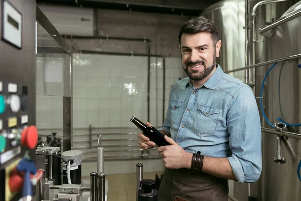 Gülümseyen adam alkol bira fabrikası, bir şişe keşfetmek — Stok fotoğraf