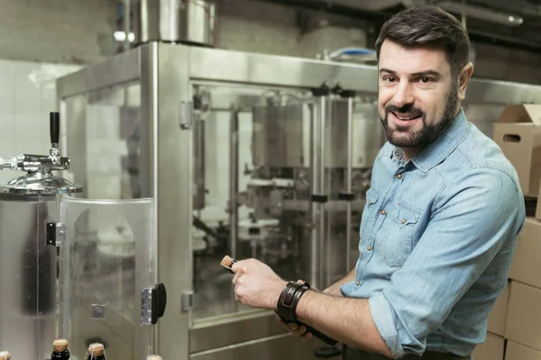 Un hombre encantado abriendo una botella de alcohol en la cervecería — Foto de Stock