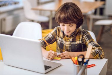 Küçük çocuk pensil ile not yazma.