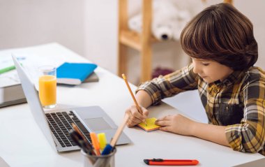 Akıllı çocuk pensil ile not yazma.