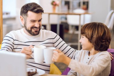 Baba ve oğul bardak çay ile tutarak