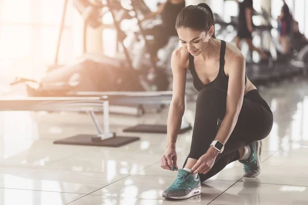 Bella donna allacciatura lacci delle scarpe in una palestra — Foto Stock