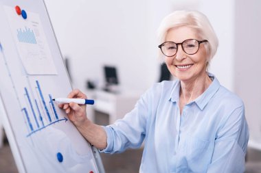 Beyaz tahta kullanarak ofiste mutlu yaşlı işkadını