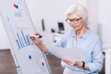 Yaşlı işkadını ofiste beyaz tahta kullanarak konsantre