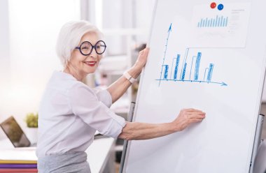 Neşeli yaşlı iş kadını ofiste beyaz tahta kullanarak