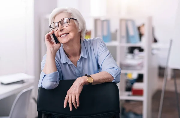 Usměvavá starší žena mluvila telefonicky v kanceláři — Stock fotografie