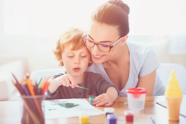 Lachende moeder onderwijs van haar zoon te trekken — Stockfoto