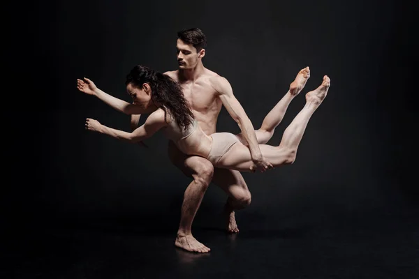 Powerful young athletes performing in front of the black wall — Stock Photo, Image