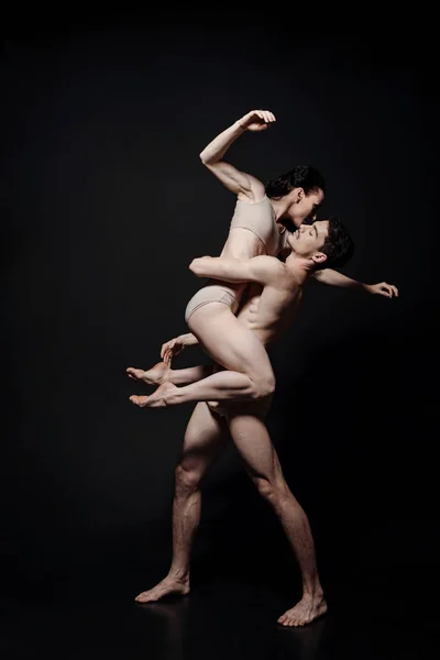 Charismatic young performers dancing in the black colored studio — Stock Photo, Image