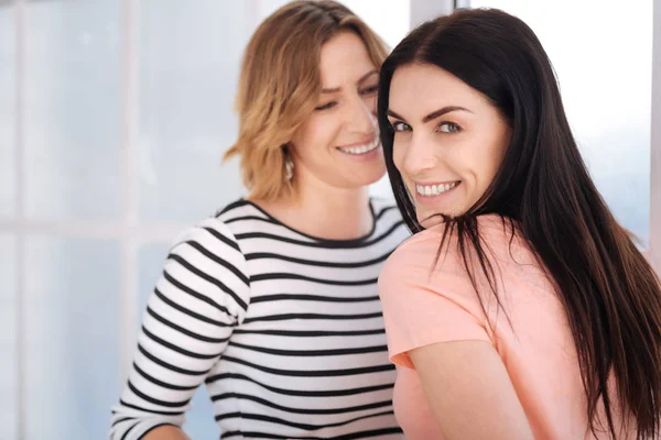 Twee vrolijke vrouwen permanent door het venster — Stockfoto