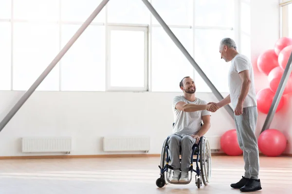 Θετική φυσιοθεραπευτής συνάντηση με ανάπηρος ασθενής στο γυμναστήριο — Φωτογραφία Αρχείου