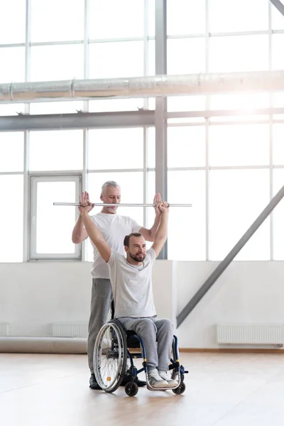 Fisioterapeuta atento haciendo gimnasia matutina con su paciente — Foto de Stock