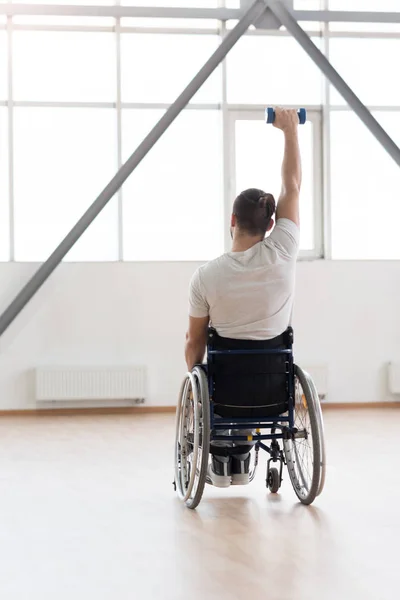 Muscular young invalid exercising with weights in gym