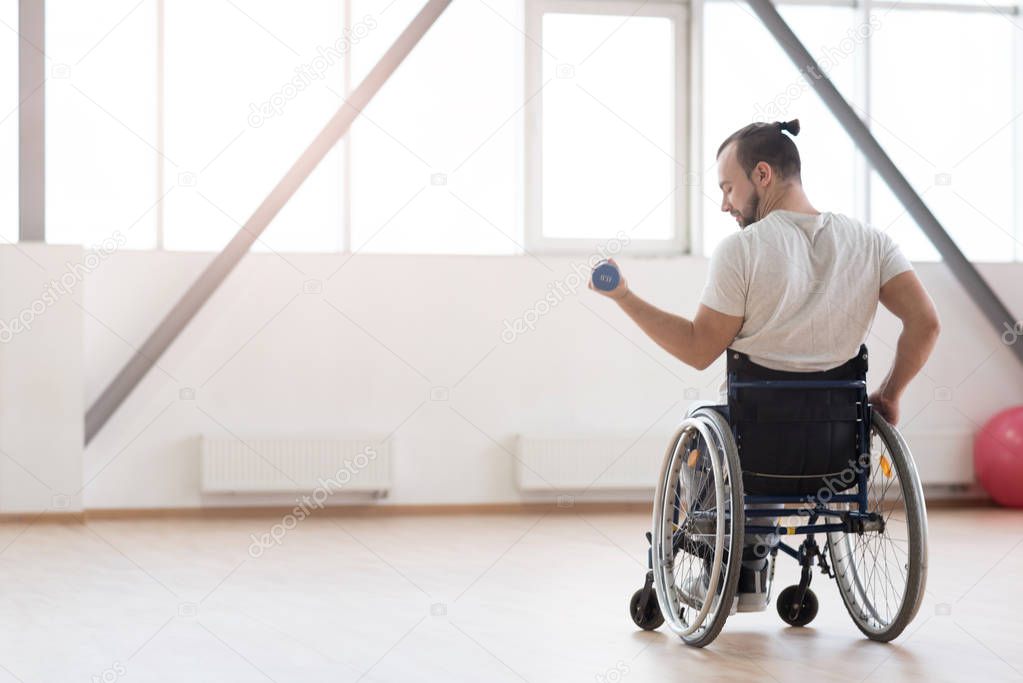 Pleasant young invalid exercising with weights in the gym