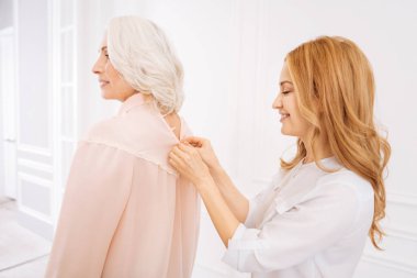 Pleasan yetişkin kadın durdurablmek annesi giyinmek için