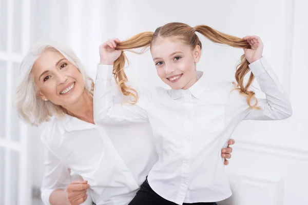 Fröhliches kleines Mädchen, das Spaß mit ihrer Großmutter hat — Stockfoto