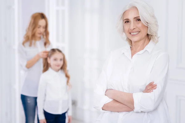 Angenehme, fröhliche Seniorin, die sich zu Hause bei ihrer Familie ausruht — Stockfoto