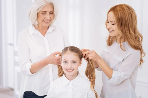 어린 소녀에 대 한 묶은 머리를 만드는 긍정적인 가족 구성원 — 스톡 사진