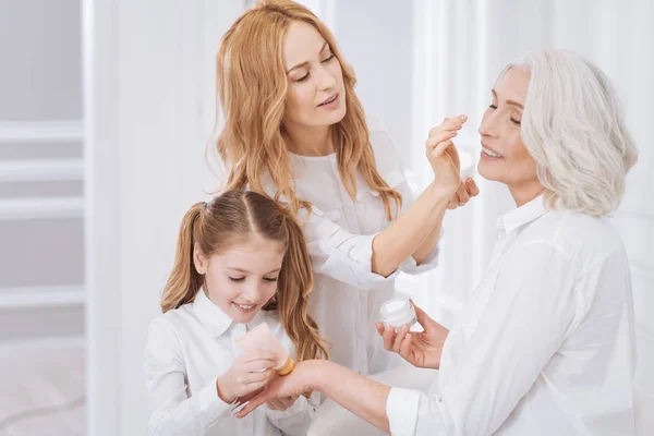 Mujer anciana agradable usando cremas de belleza — Foto de Stock