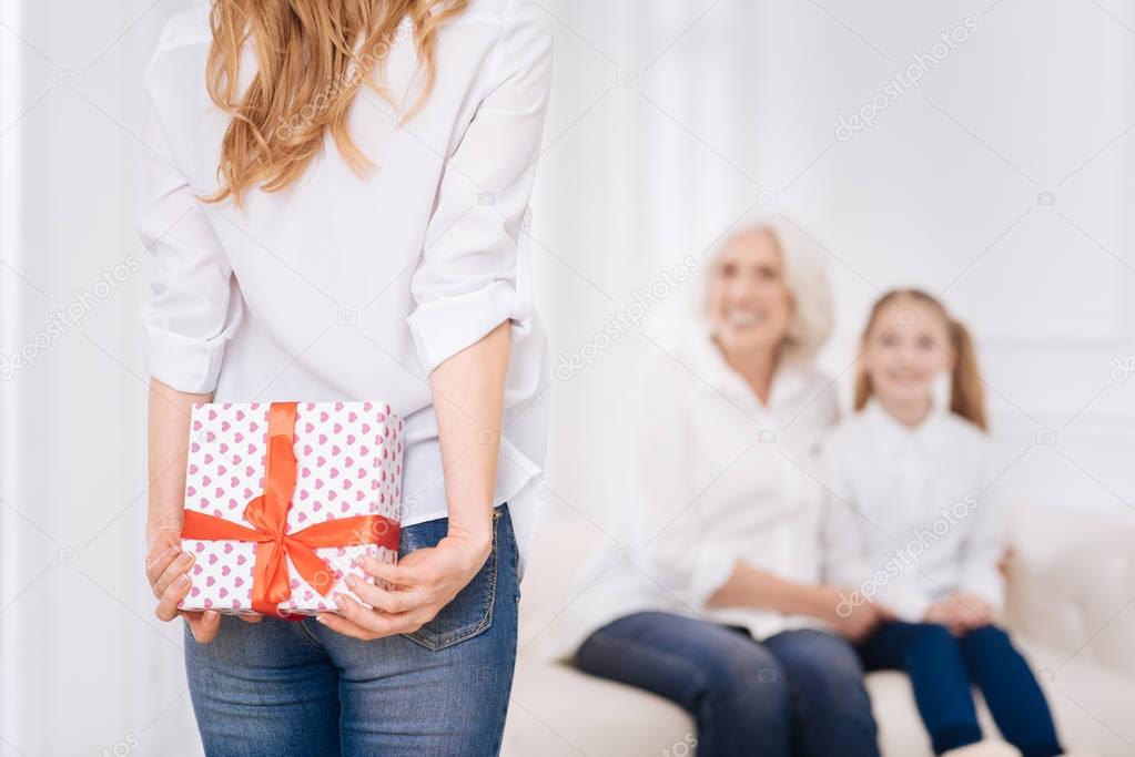 Pleasant adult woman holding present behind her back