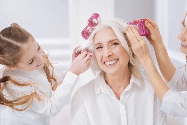 Fröhliche ältere Frau, die sich die Haare kräuselt — Stockfoto