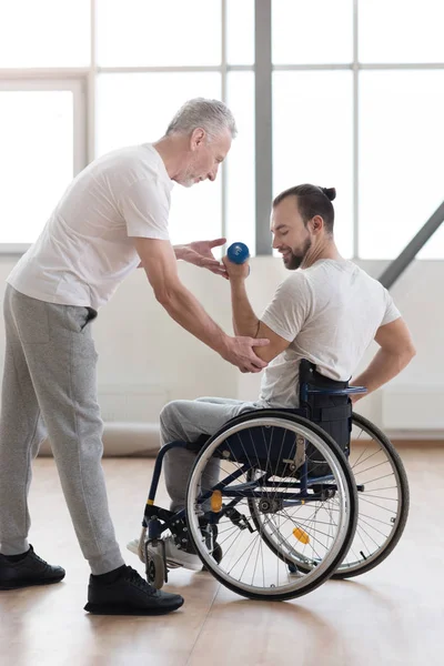 Hombre con discapacidad de confianza haciendo ejercicio con su entrenador en el gimnasio —  Fotos de Stock