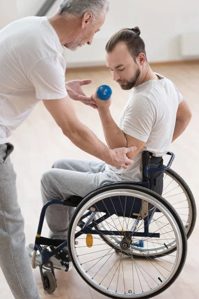 Zaangażowanych niepełnosprawny mężczyzna wykonujący rezygnować jego trener na siłowni — Zdjęcie stockowe