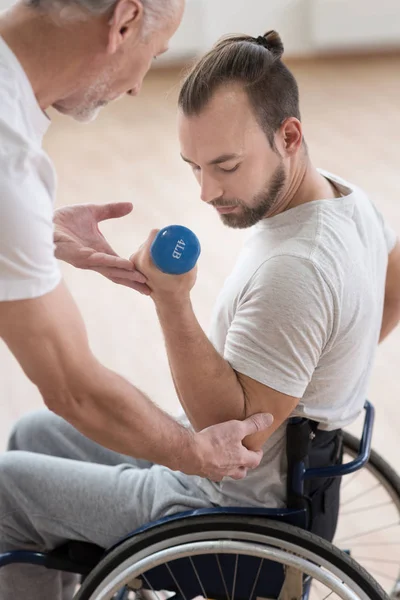 Skoncentrowany niepełnosprawny mężczyzna wykonujący rezygnować jego trener na siłowni — Zdjęcie stockowe