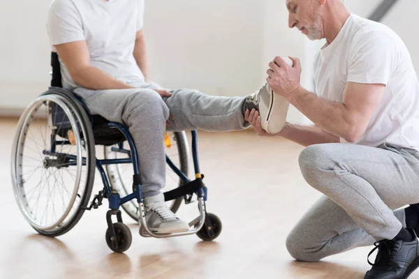 Ortopedista idoso trabalhando com deficientes no ginásio — Fotografia de Stock