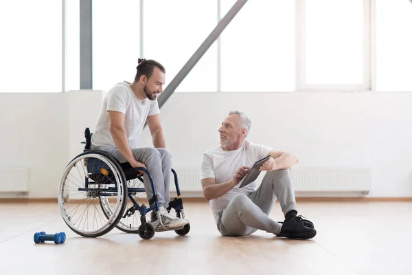 Ortopedista alegre que comunica com o paciente com deficiência no ginásio — Fotografia de Stock