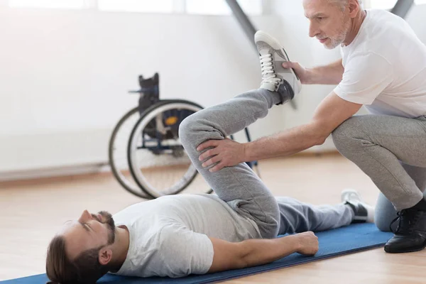 Skillful coach helping the handicapped in the gym — Stock Photo, Image