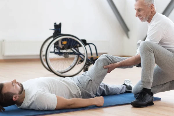 Ortopedista carismático estirando a los discapacitados en el gimnasio — Foto de Stock