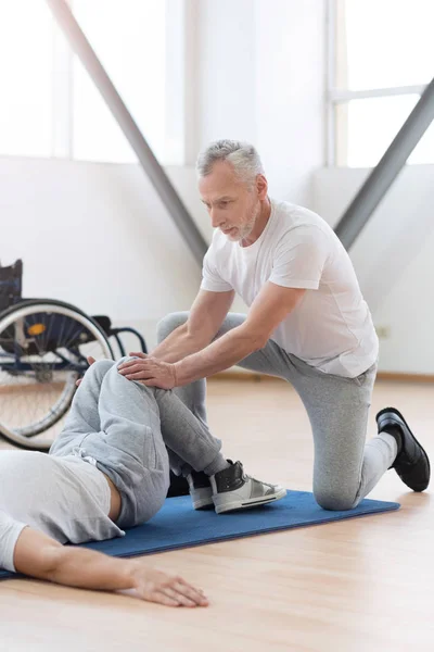 Médico general de edad que estira a los discapacitados en el gimnasio — Foto de Stock