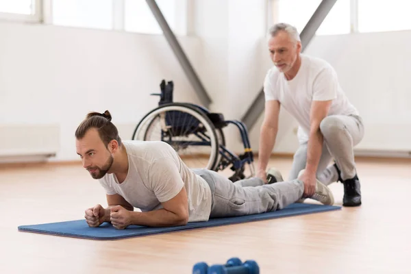 Fredliga sjukgymnast stretching handikappade patienten i gymmet — Stockfoto