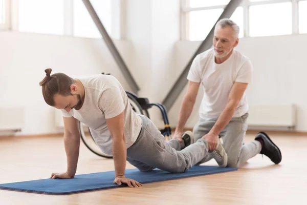 Stödjande sjukgymnast stretching handikappade i gymmet — Stockfoto