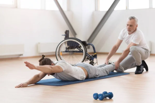 Pomocne Fizjoterapeuta rozciąganie osób niepełnosprawnych w siłowni — Zdjęcie stockowe
