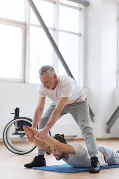 Erfaren sjukgymnast som arbetar med funktionshindrade i gymmet — Stockfoto