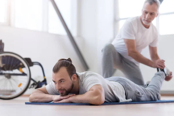 Aged bearded father stretching his disabled son in the gym — Stock Photo, Image